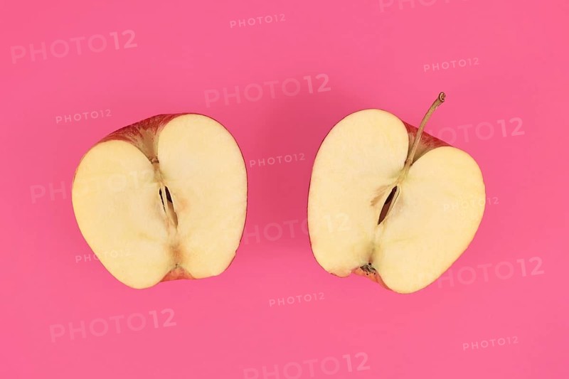 Apple cut into half on pink background,