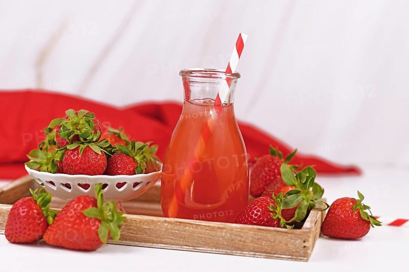 Jar with strawberry fruit lemonade surrounded by berries,