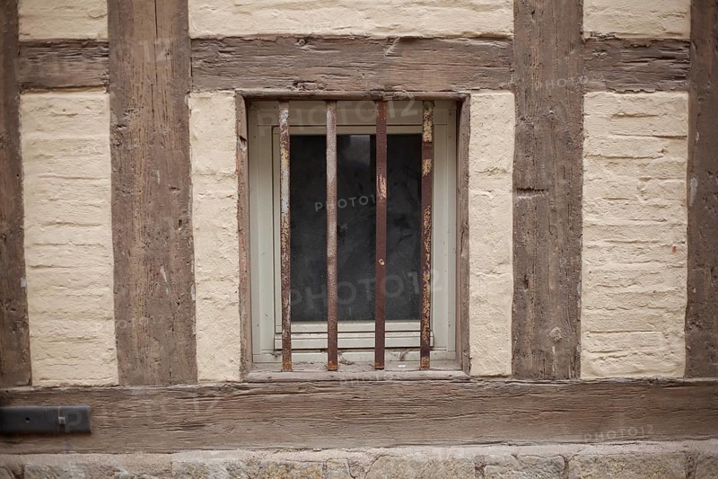 Old window with window grille on a brown house wall with half-timbered beams, Quedlinburg