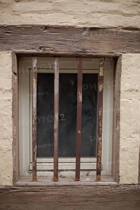 Old window with window grille on a brown house wall with half-timbered beams, Quedlinburg