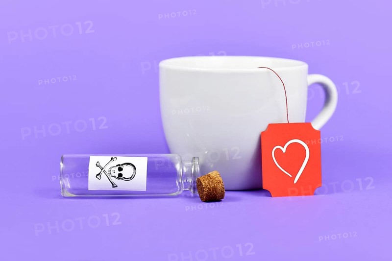 Empty open vial with cork and poison skull label next to tea cup with heart on red label on purple background,