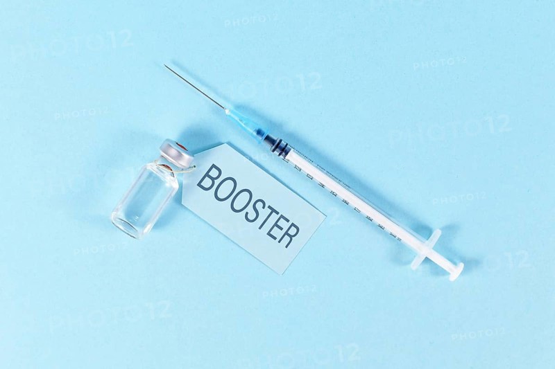 Concept for Corona virus booster vaccination with vial and syringe on blue background,