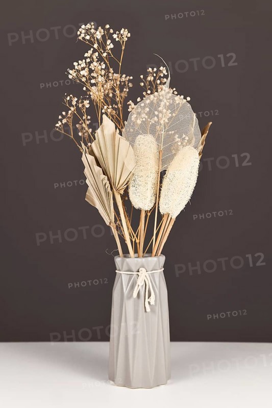 Natural bouquet wit gray vase with dried flowers and leaves like palm leaf, skeleton leaf