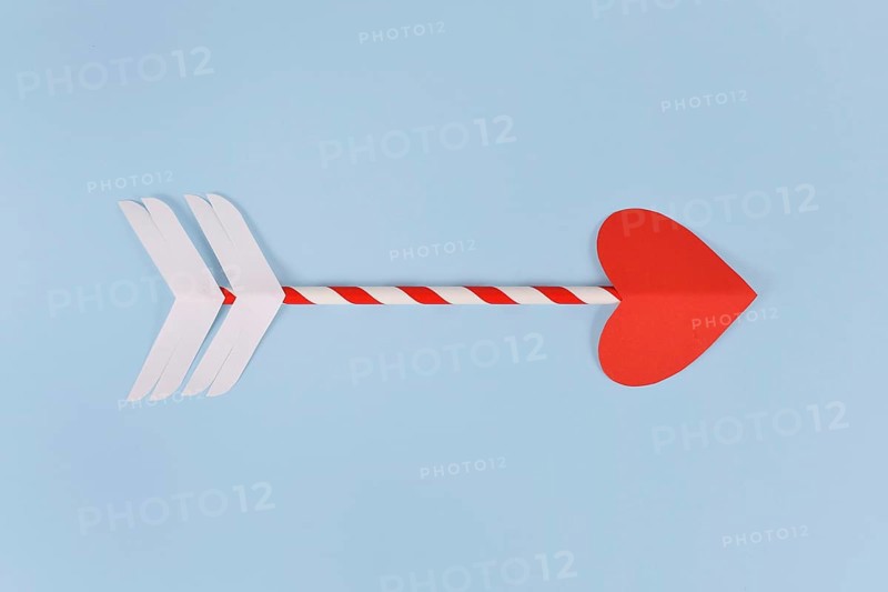 Simple paper cupid love arrow with heart shaped tip on blue background,