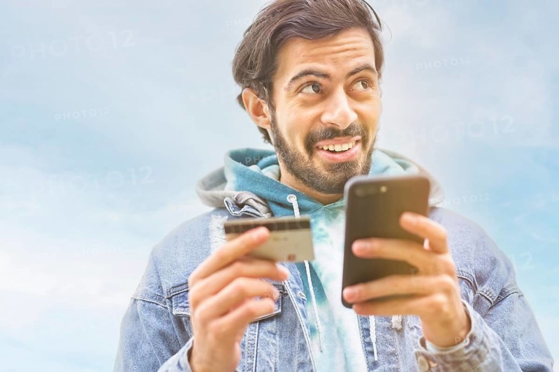 Latin man using credit card to make online payment on smartphone. mixed-race man using cellphone for shopping online. Guy using smart phone to check credit card transactions from app. Copy space,