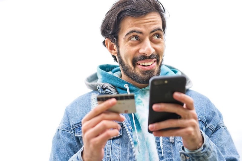 Latin man using credit card to make online payment on smartphone. mixed-race man using cellphone for shopping online. Guy using smart phone to check credit card transactions from app. White background,