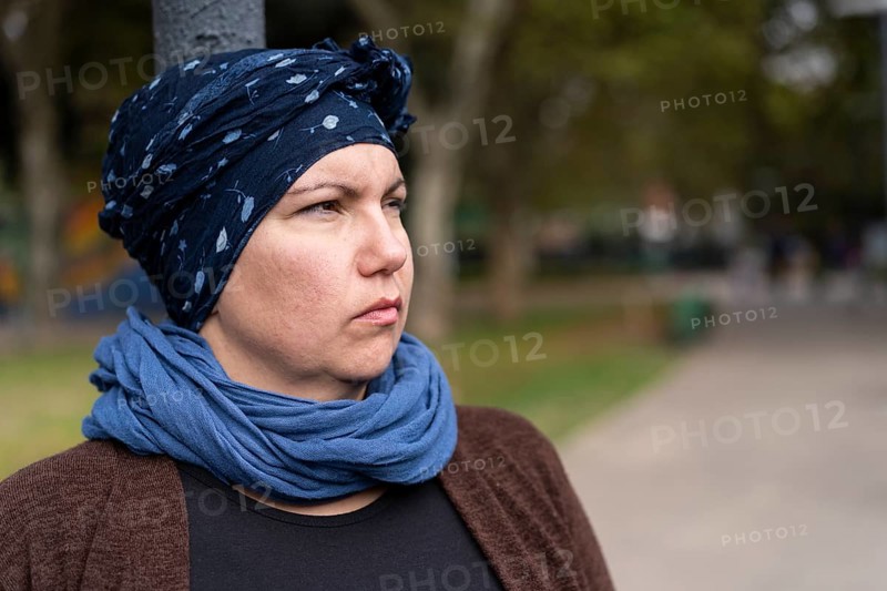 Portrait of a Latin woman undergoing cancer treatment with her head covered by a scarf with an expression of strength,