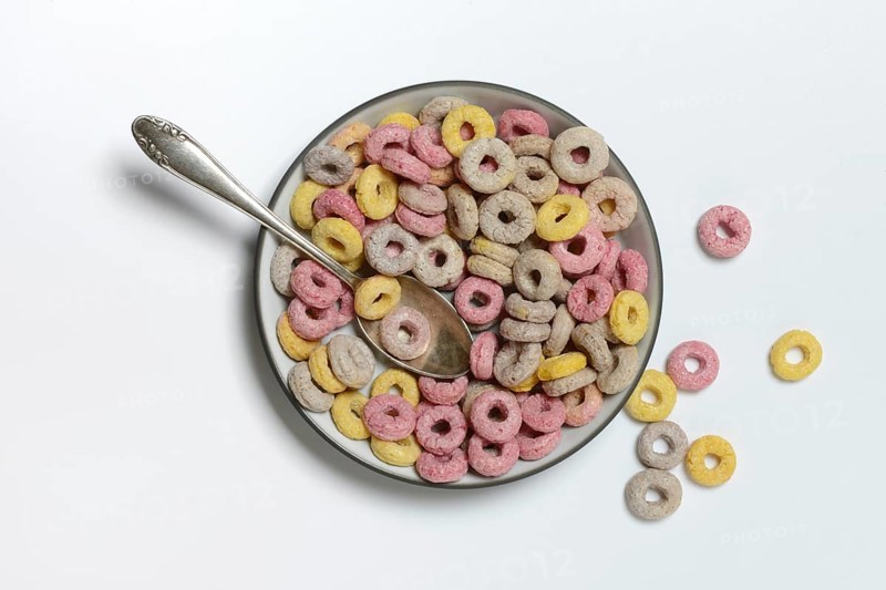 Fruit-flavoured cereal rings in bowl and spoon, children's breakfast
