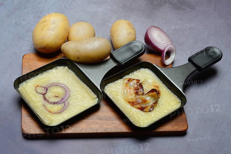 Raclette, melted raclette cheese in pans and ingredients