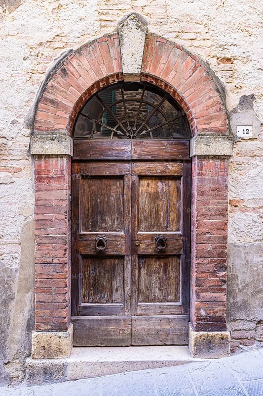 Weathered old round arch front door, Motepulciano