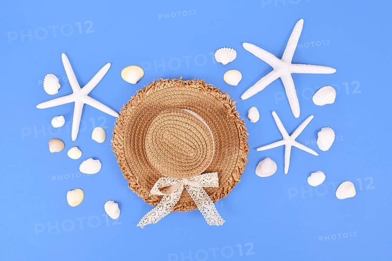 White starfish, seashells and summer straw hat on blue background