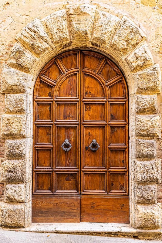 Round arched house entrance door, framed with light-coloured stones