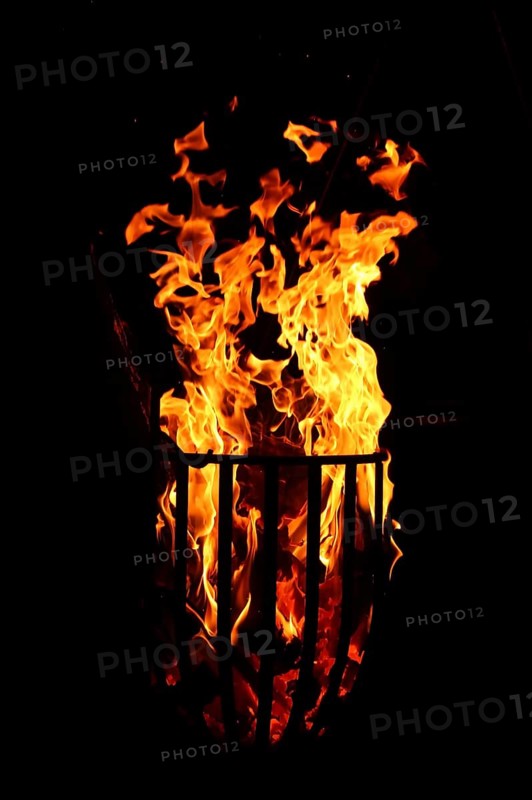 Metal fire basket with burning wood at night,