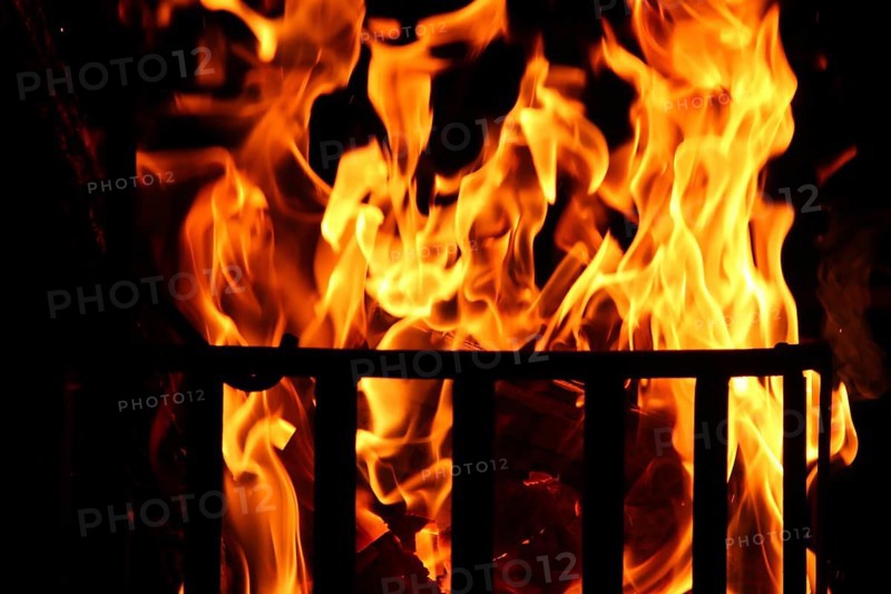 Metal fire basket with burning wood at night,