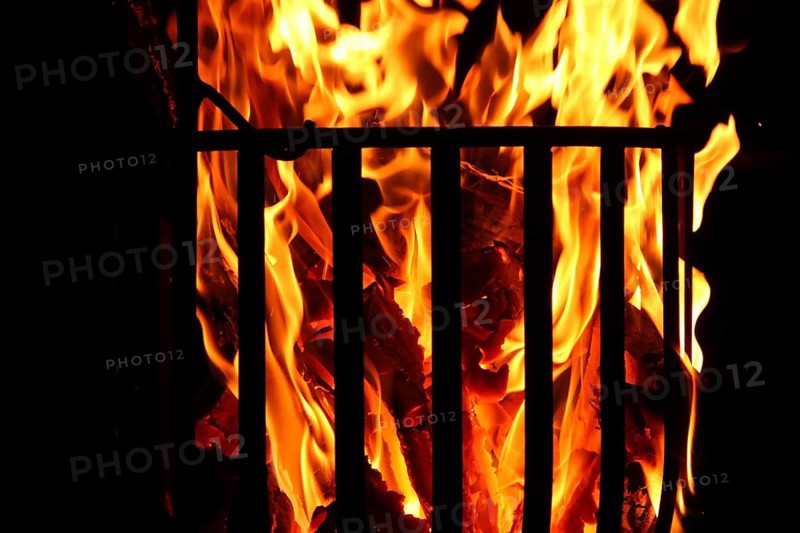 Metal fire basket with burning wood at night,