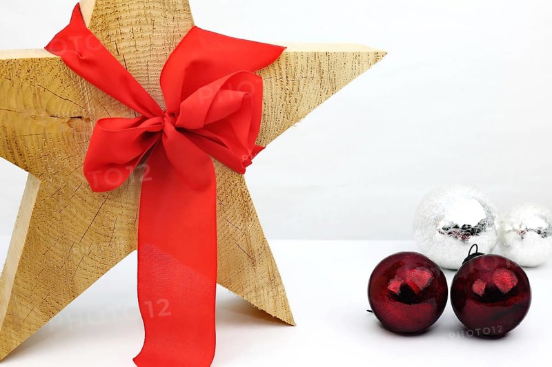 Christmas wooden star with a red bow on a white background, silver and red Christmas tree balls on the side