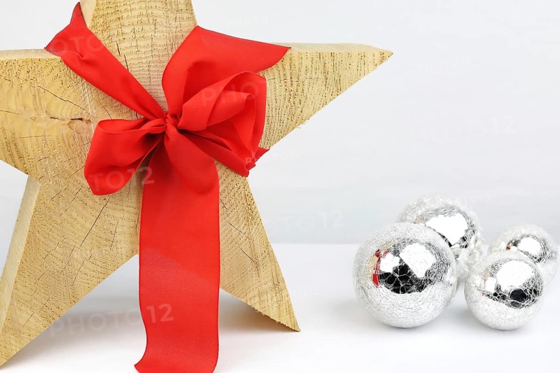 Christmas wooden star with a red bow on a white background, silver Christmas tree balls on the side