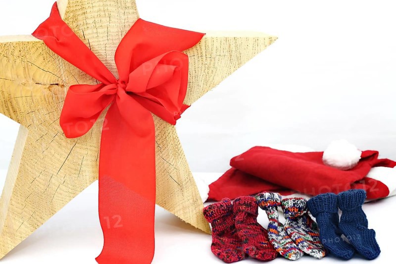 Christmas wooden star with a red bow isolated against a white background, Self-knitted socks on the side