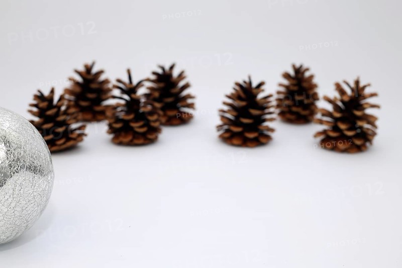 Silver Christmas tree ball and fir cone or pine cone cropped against white background with sharpening gradient,