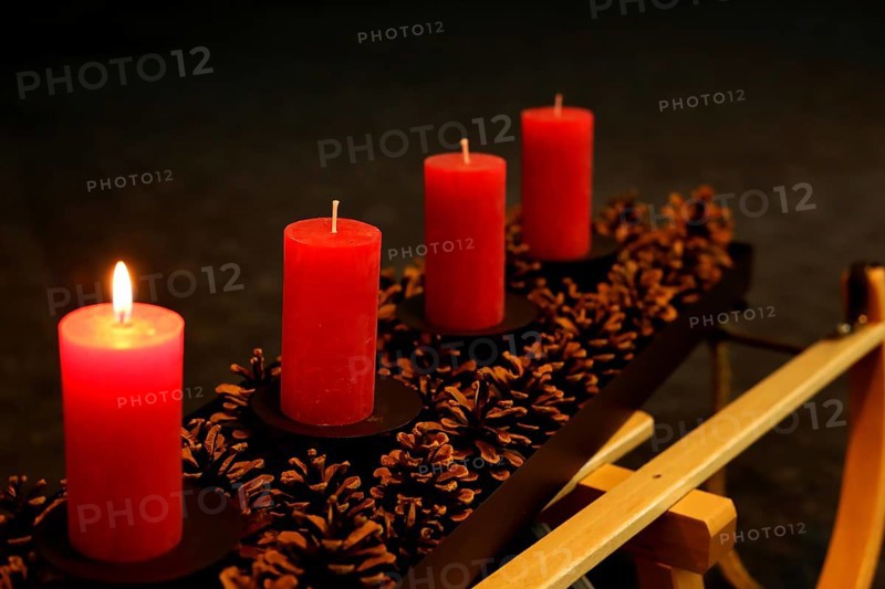 Four Advent candles decorated with pine cones on a sleigh, First Advent one candle burning