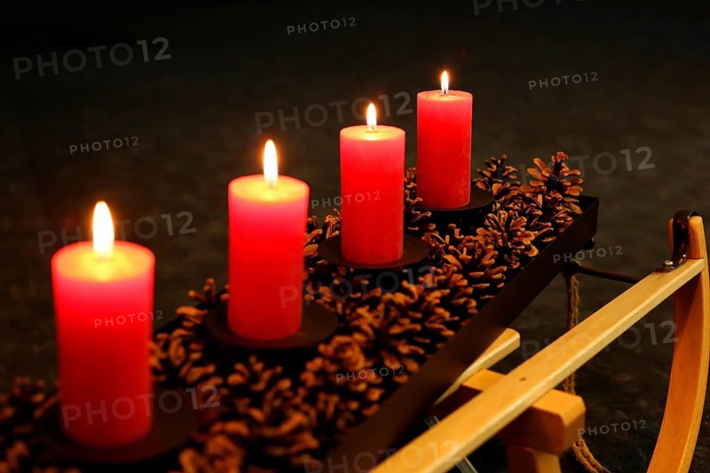 Four Advent candles decorated with pine cones on a sleigh, Fourth Advent four candles burning