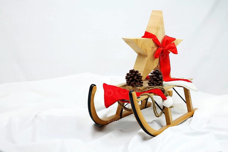 Christmas wooden star with a red bow on a sleigh cut out against a white background,