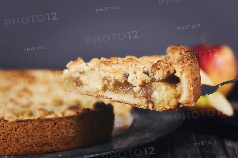 Single slice of traditional European apple pie with topping crumbles on cake server,