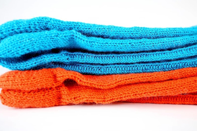 Self-knitted socks made of wool isolated against a white background in orange and blue,