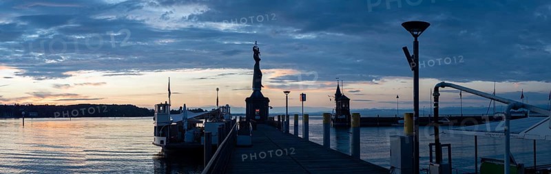 Statue of Imperia at the harbour entrance of Constance in the morning light in front of sunrise, Old Town