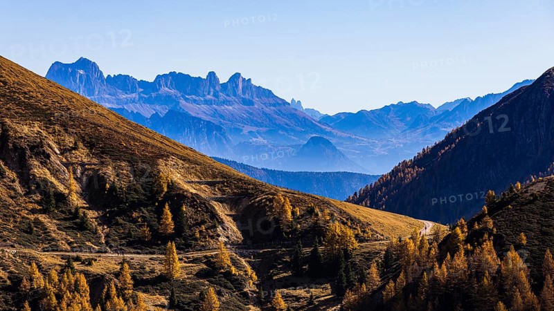 Hiking trail in autumnal mountain landscape, the mountain backdrop of the Dolomites in the background