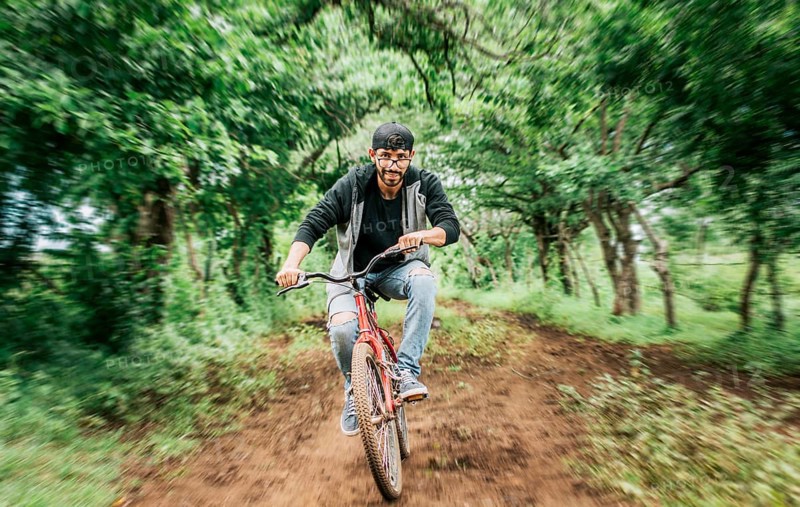 Portrait of a guy in cap riding a bike on a country road, Person riding a bike in the countryside