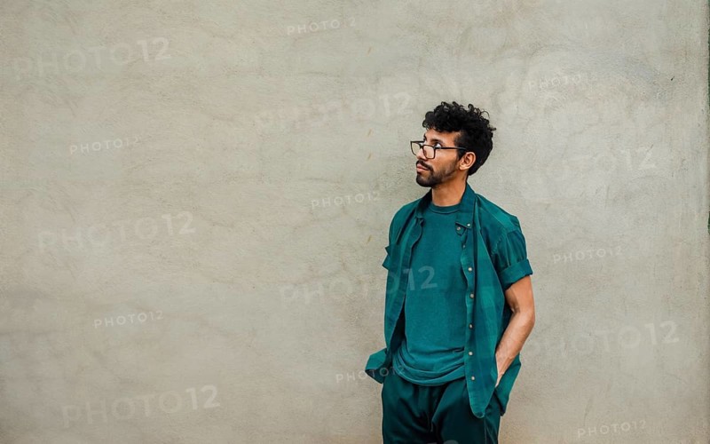 Pensive handsome man leaning on a wall looking up, worried male with hands in pocket looking up