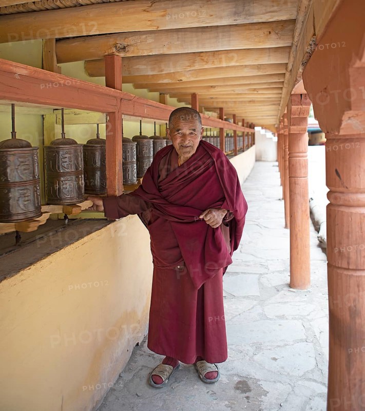 A monk with prayer wheels on a wall of Hemis Gompa, Hemis