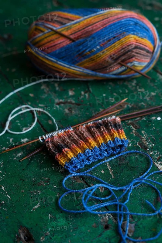 Handwork, knitted sock with knitting needles and wool
