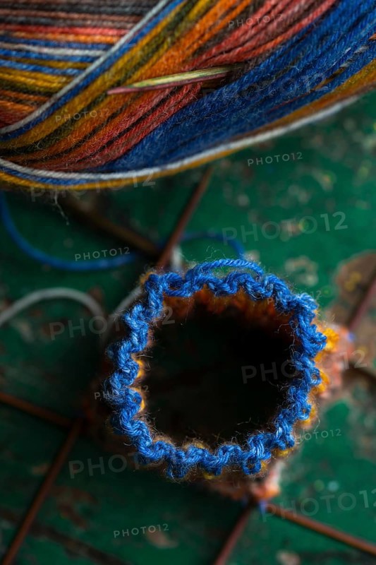 Handwork, knitted sock with knitting needles and wool