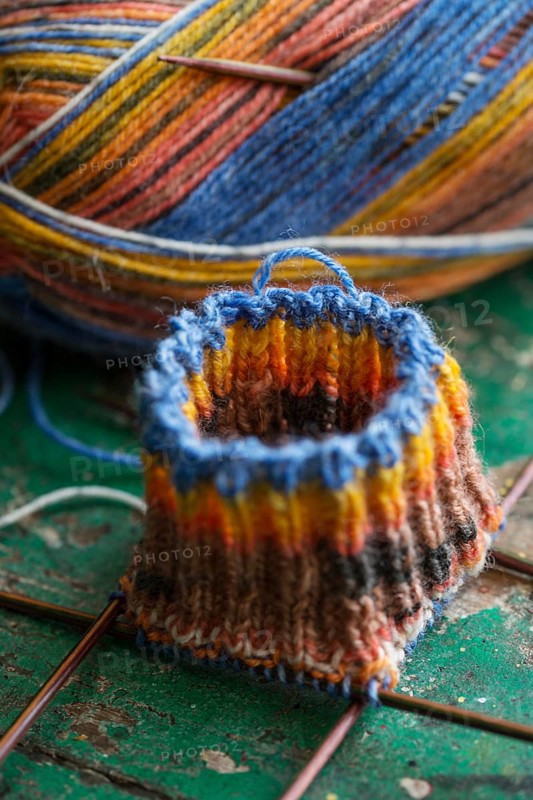 Handwork, knitted sock with knitting needles and wool