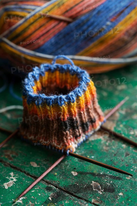 Handwork, knitted sock with knitting needles and wool