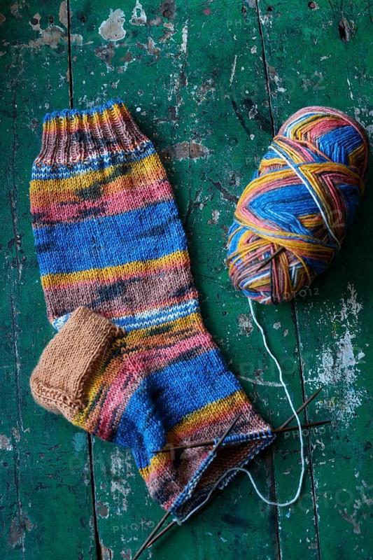 Handwork, knitted sock with knitting needles and wool