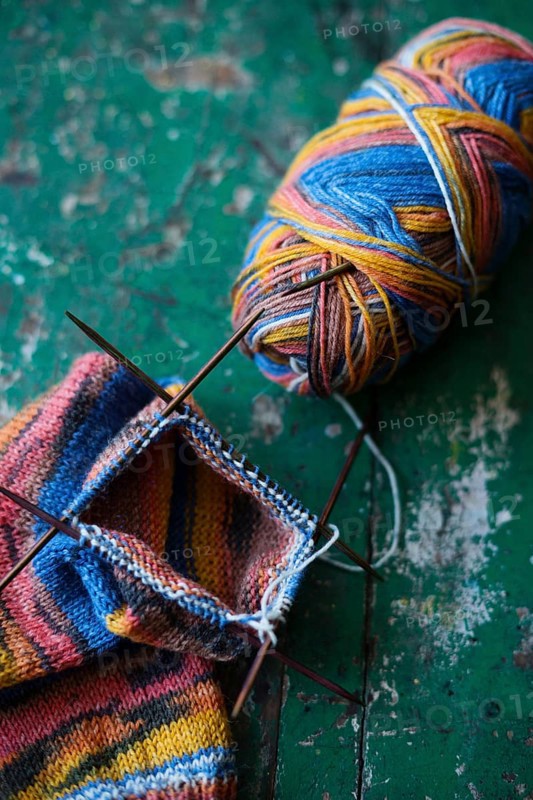 Handwork, knitted sock with knitting needles and wool