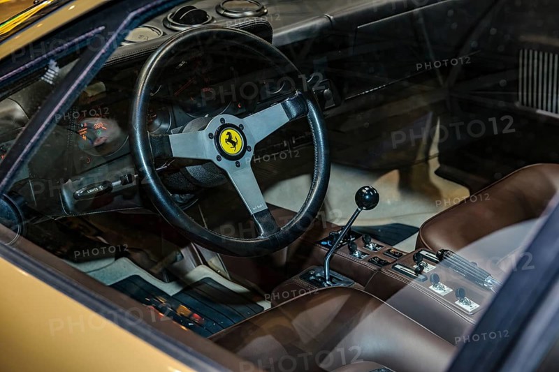 View into interior of Ferrari 512 BB from 70s 1977 with steering wheel with logo jumping horse Cavallino Rampante and lever of manual gear shift, fair Techno Classica