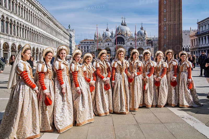 Group of woman in Renaissance robes on St Mark's Square with St Mark's Basilica, Venice