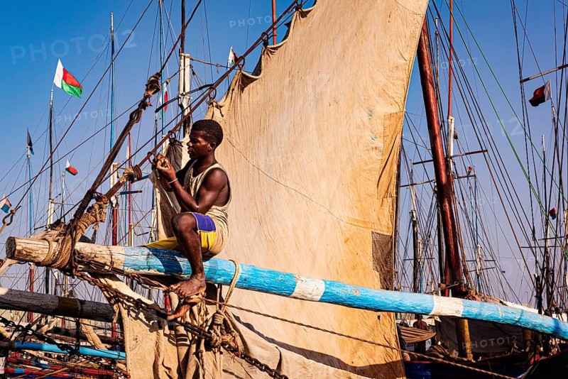 Man sitting on the yard of a fishing boat in the Arab quarter, yard sail behind