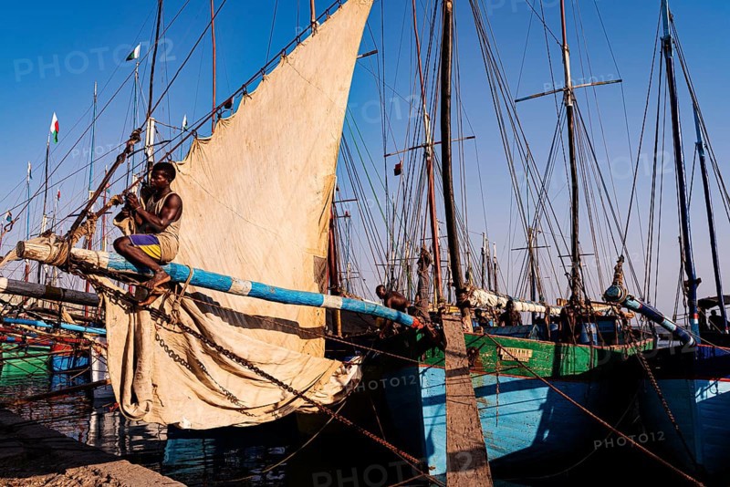 Man sitting on the yard of a fishing boat in the Arab quarter, yard sail behind