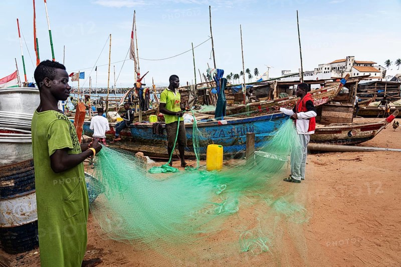Fishermen mending nets, fishing boats