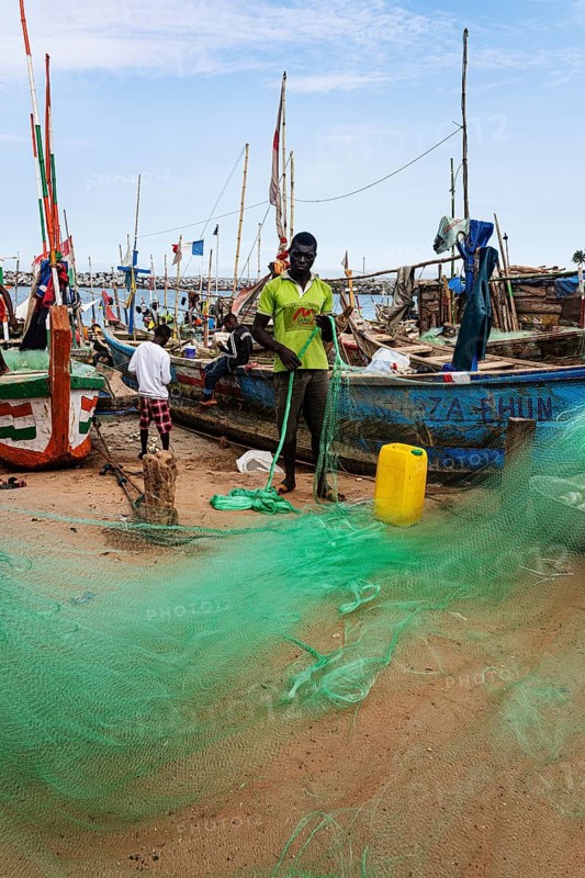 Fishermen mending nets, fishing boats