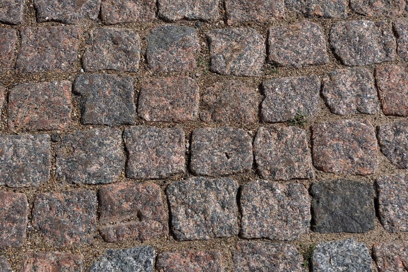 Cobblestone pavement. Texture of cobblestone road close-up. Part of the road paved with red black granite