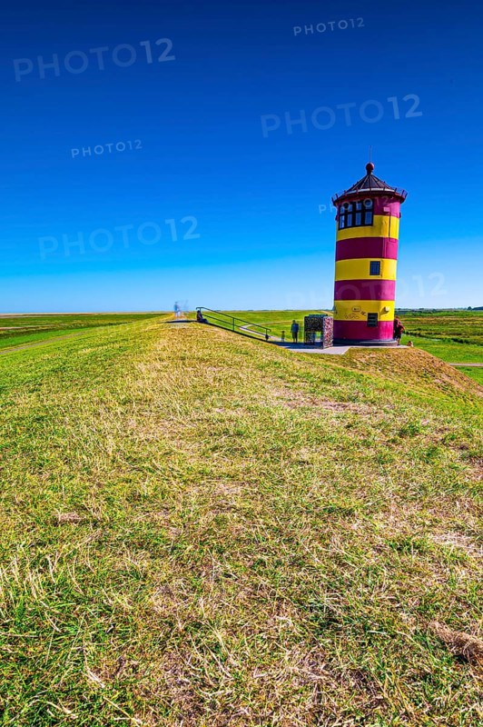 The Pilsum lighthouse on the dike in summer near Greetsiel on the North Sea