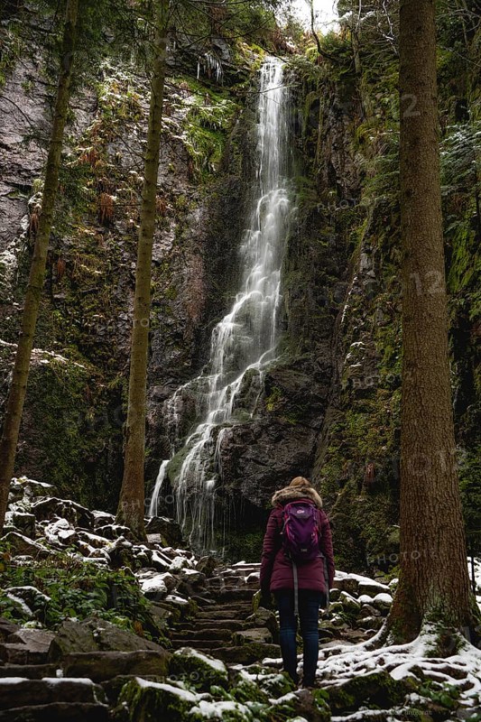 Woman in front of waterfall in winter landscape
