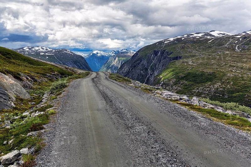 Gravel road through barren mountain landscape with remnants of snow