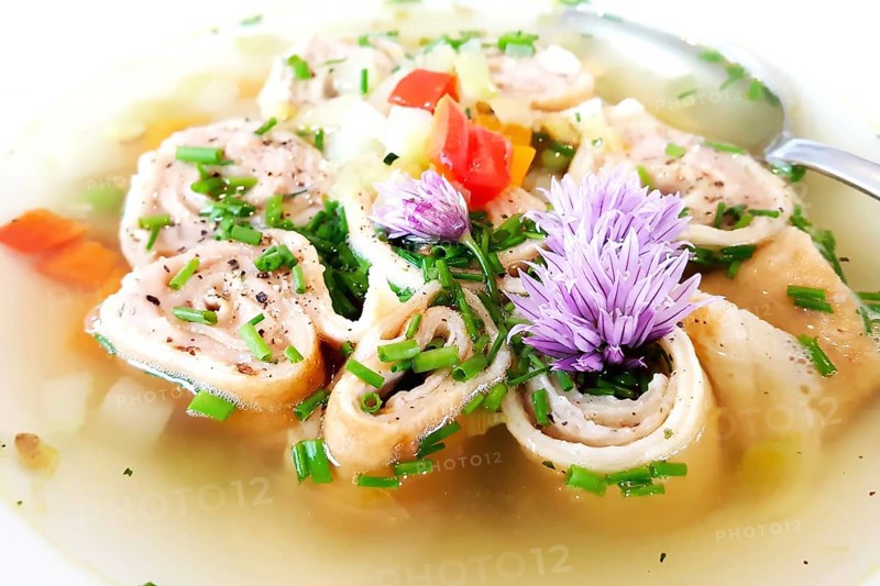 Delicious Braet Strudel soup served in a plate and garnished with chives and chive blossoms